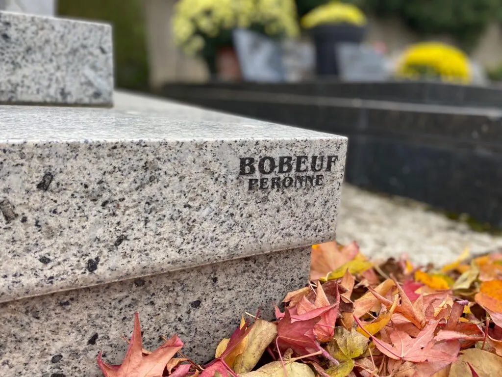 Gros plan sur une pierre tombale en granit gravée de la signature du marbrier