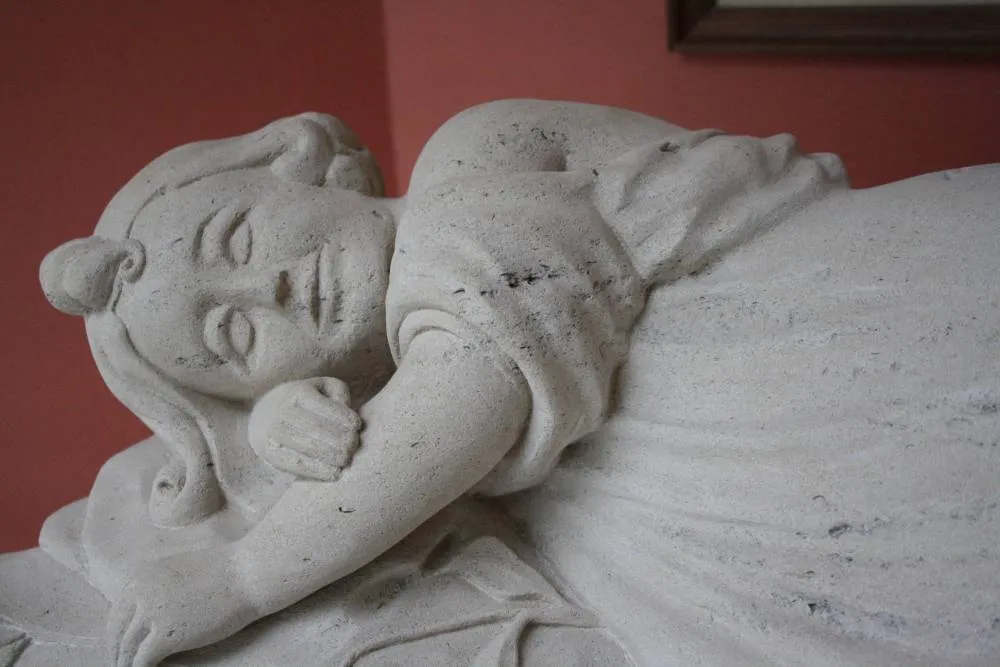 Gisant sculpté dans la pierre blanche représentant un personnage endormi sur une sépulture