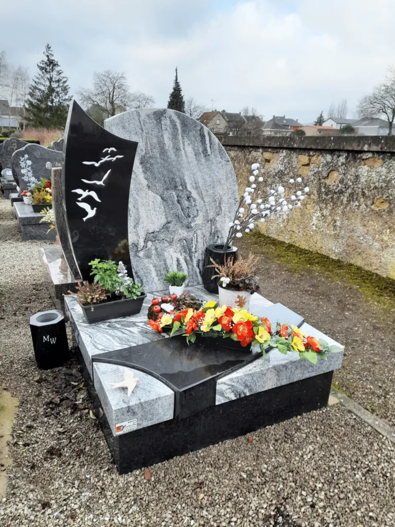 Monument funéraire en granit veiné orné de gravures d'oiseaux et de fleurs